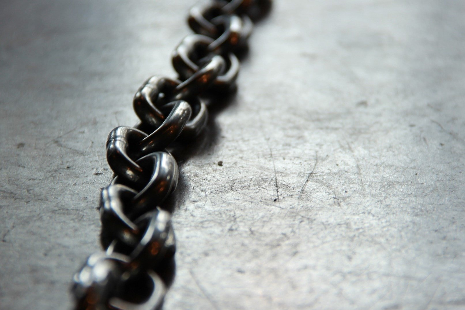 Dark grey metal chain on a light grey background.