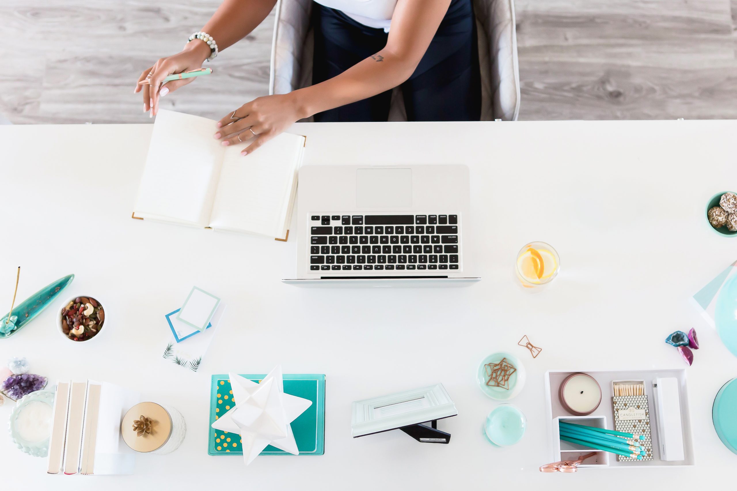 Overhead of desk with woman looking at her notebook to the side of her laptop