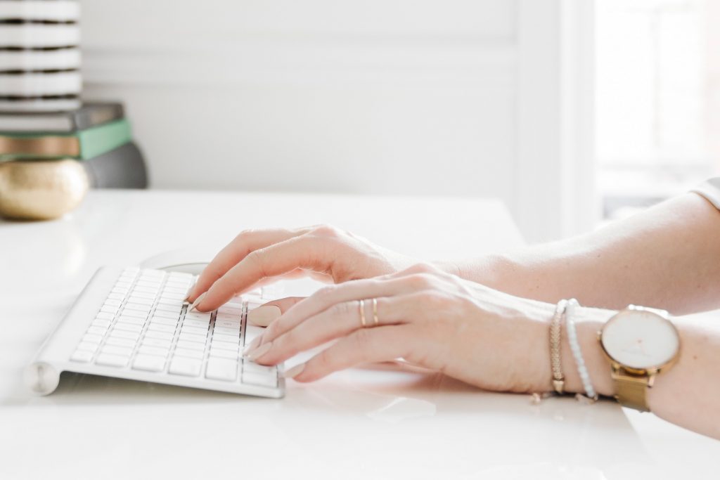 Woman typing on a white keyboard