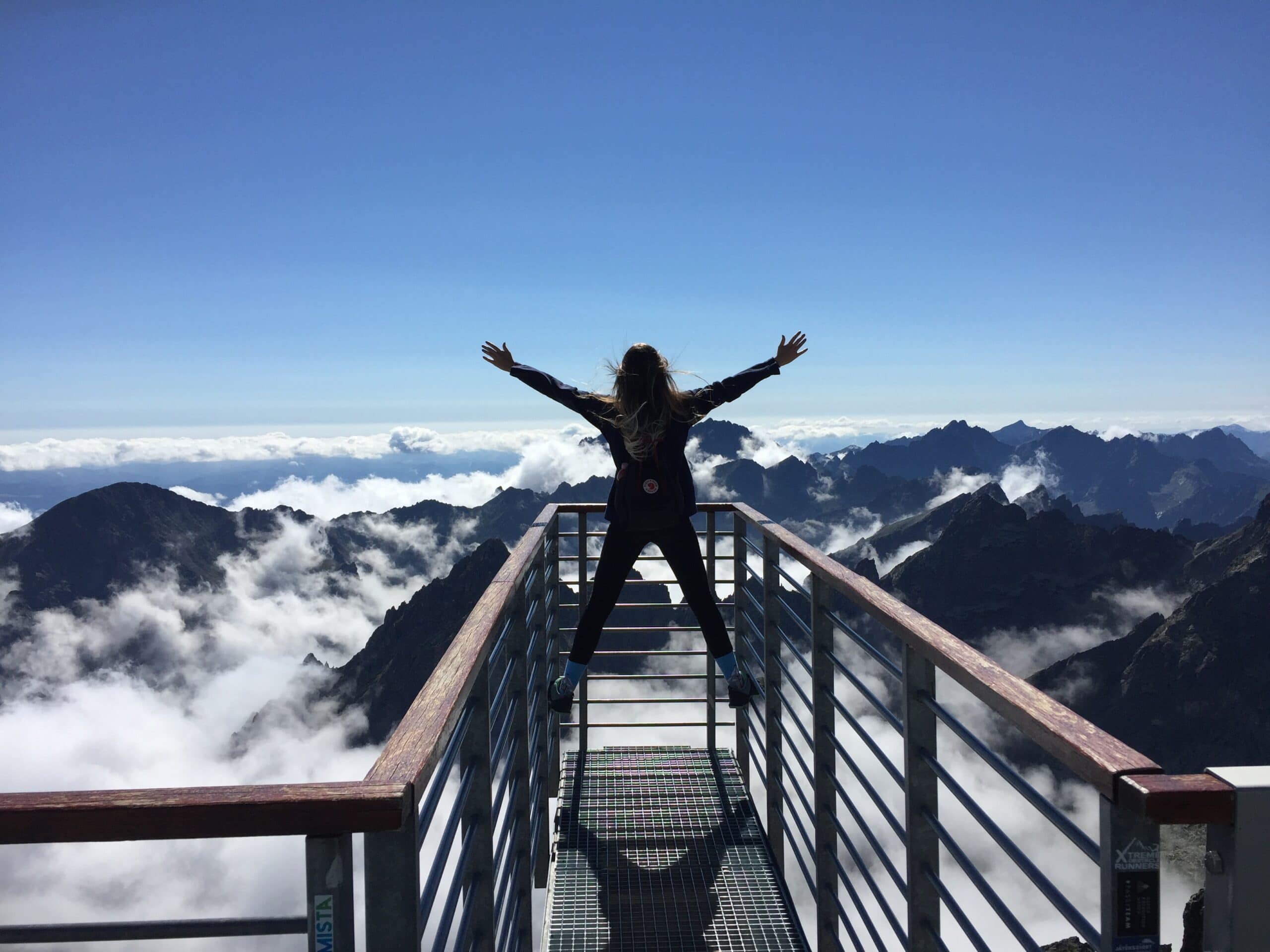 Woman standing at the top of a mountain with her hands outstretched